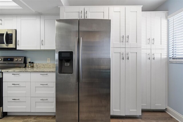 kitchen featuring dark hardwood / wood-style floors, light stone countertops, white cabinetry, and stainless steel appliances