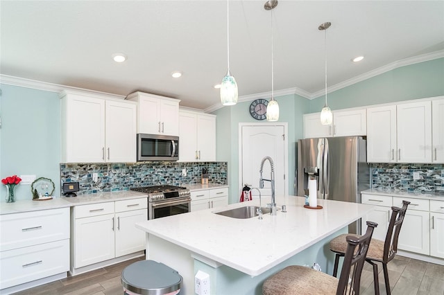 kitchen featuring appliances with stainless steel finishes, tasteful backsplash, sink, pendant lighting, and an island with sink