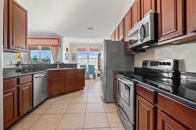 kitchen with light tile patterned flooring, sink, hanging light fixtures, dark stone counters, and stainless steel appliances