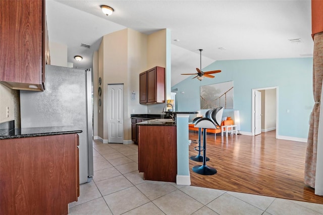 kitchen featuring a breakfast bar, sink, light tile patterned floors, ceiling fan, and kitchen peninsula