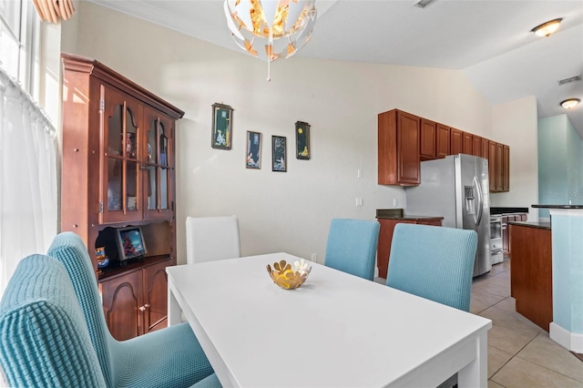 tiled dining space with lofted ceiling and a notable chandelier