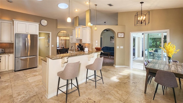32 Woodward Ln, Palm Coast, FL 32164 - kitchen featuring freestanding refrigerator, arched walkways, light stone counters, a kitchen breakfast bar, and high vaulted ceiling