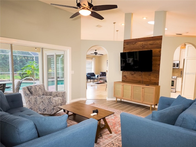 living room with ceiling fan, light hardwood / wood-style floors, and a high ceiling