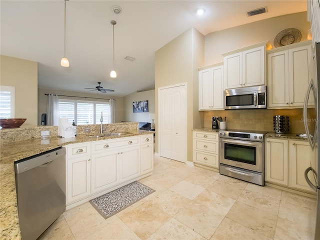 kitchen with pendant lighting, sink, vaulted ceiling, light stone countertops, and appliances with stainless steel finishes