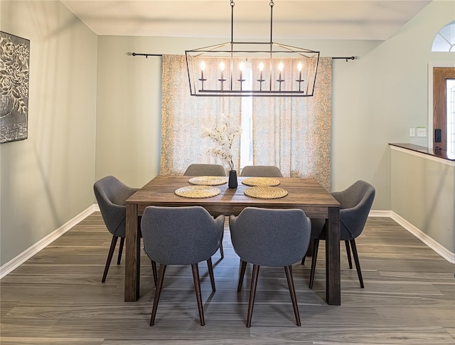 dining area with dark hardwood / wood-style flooring and an inviting chandelier