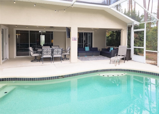 view of pool with outdoor lounge area, a patio area, and glass enclosure