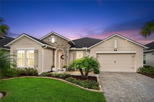 single story home featuring a garage and a lawn