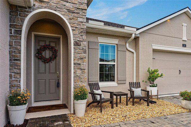 597 Mosaic Blvd, Daytona Beach, FL 32124 - view of exterior entry featuring stone siding, an attached garage, and stucco siding