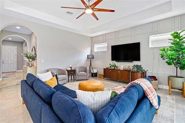 living room with a tray ceiling and ceiling fan