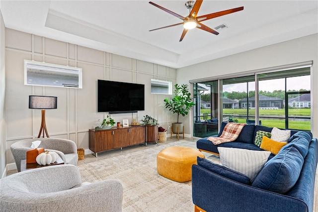 living room featuring a tray ceiling and ceiling fan