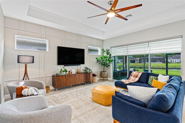 living room with a tray ceiling and ceiling fan