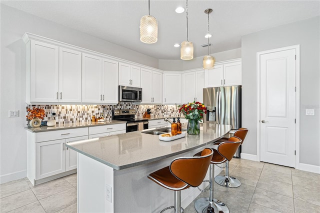 kitchen featuring sink, stainless steel appliances, an island with sink, pendant lighting, and white cabinets