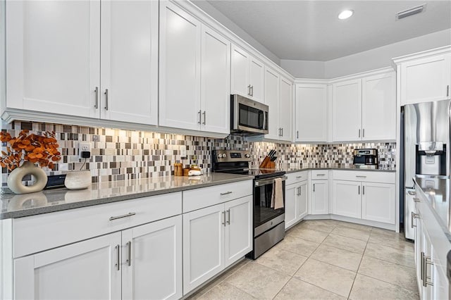 kitchen featuring white cabinets, appliances with stainless steel finishes, backsplash, and light stone counters