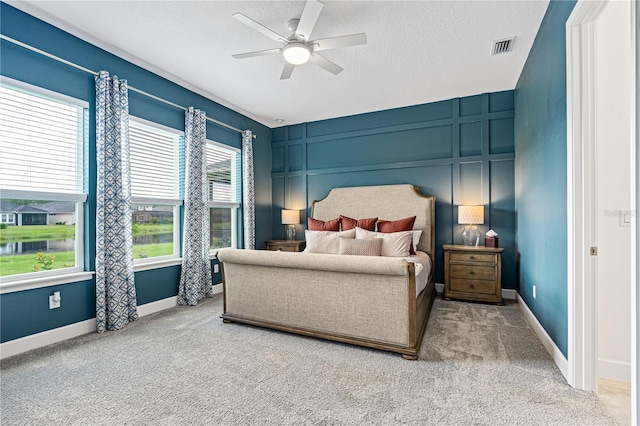 carpeted bedroom with ceiling fan, multiple windows, and a textured ceiling