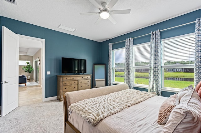 carpeted bedroom featuring multiple windows, ceiling fan, and a textured ceiling