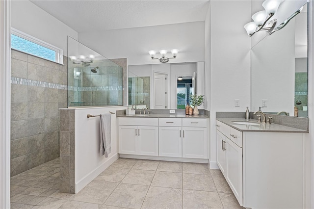 bathroom with vanity, a tile shower, tile patterned floors, and a textured ceiling