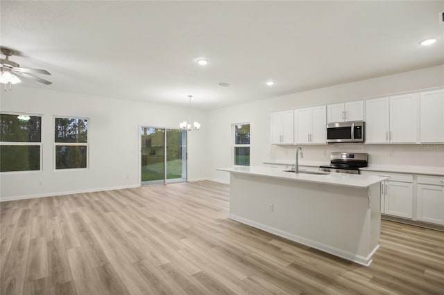 kitchen featuring sink, white cabinets, hanging light fixtures, light wood-type flooring, and stainless steel appliances