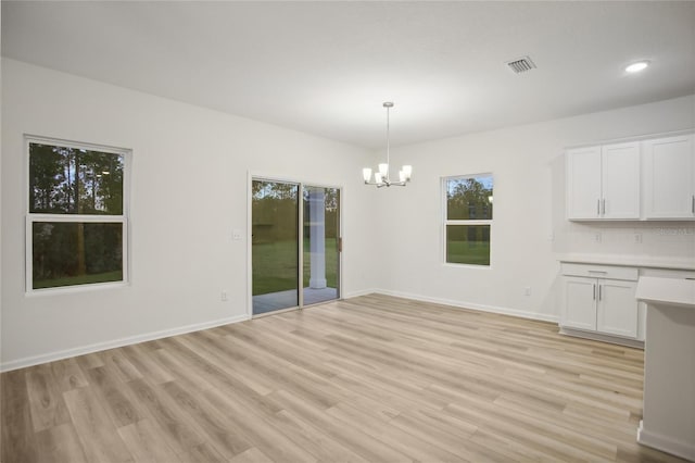 unfurnished dining area featuring light hardwood / wood-style flooring and a chandelier