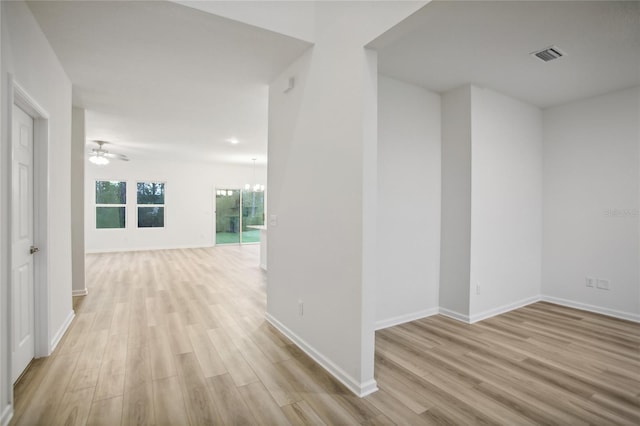 corridor with light hardwood / wood-style floors and a notable chandelier