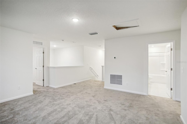 spare room with light colored carpet and a textured ceiling