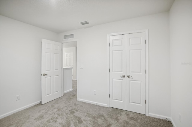 unfurnished bedroom featuring a closet and light colored carpet