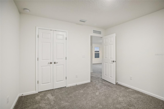 unfurnished bedroom featuring carpet flooring, a textured ceiling, and a closet