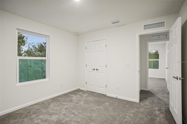 unfurnished bedroom featuring a closet, dark carpet, and a textured ceiling