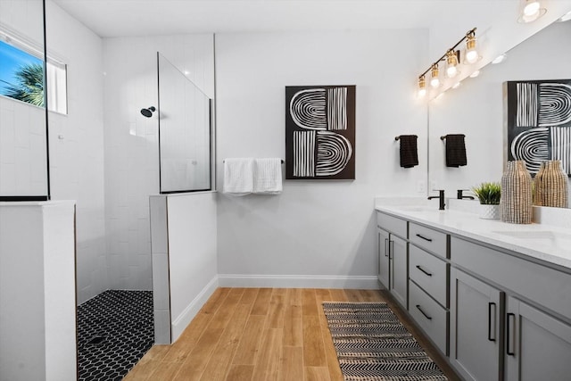 bathroom with a tile shower, vanity, and wood-type flooring