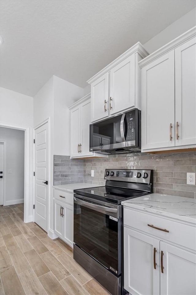 kitchen featuring white cabinets, wood tiled floor, stainless steel appliances, and backsplash