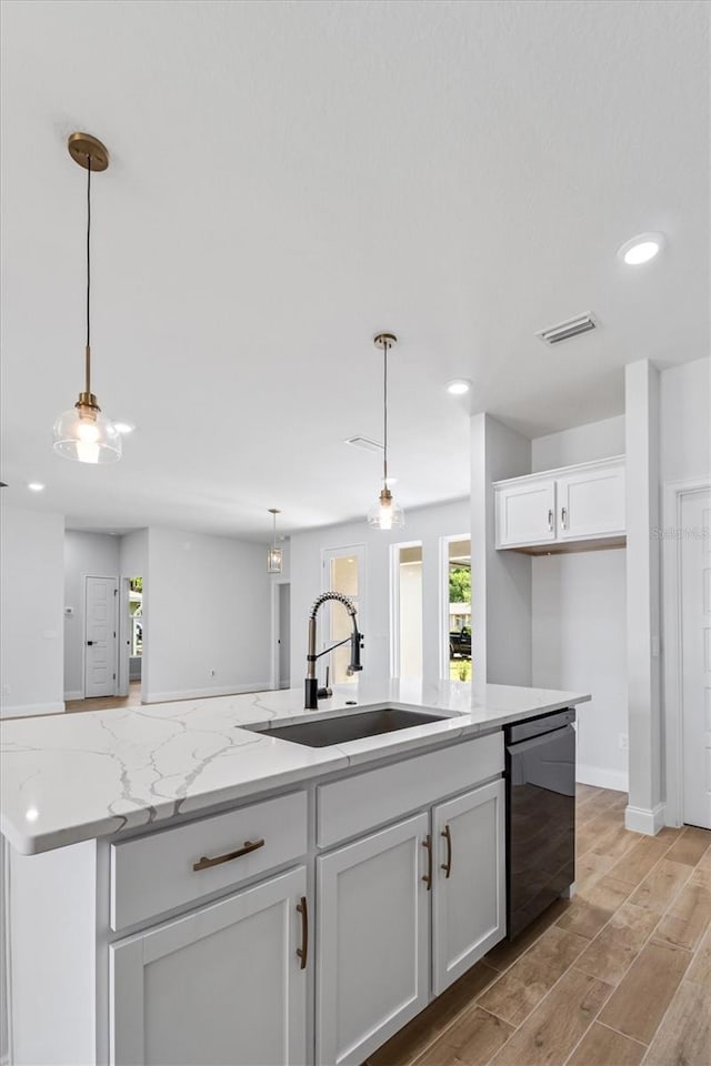 kitchen with white cabinets, visible vents, light wood finished floors, dishwasher, and a sink