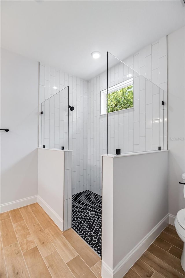 full bath with baseboards, wood finished floors, toilet, and a walk in shower