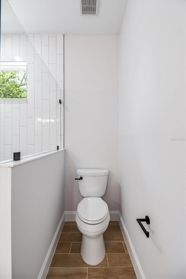 full bath featuring visible vents, baseboards, toilet, wood finish floors, and a walk in shower