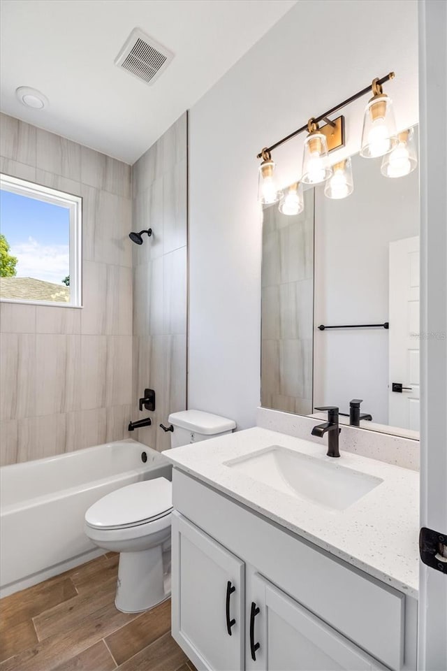 bathroom featuring visible vents, toilet, wood finished floors, vanity, and  shower combination