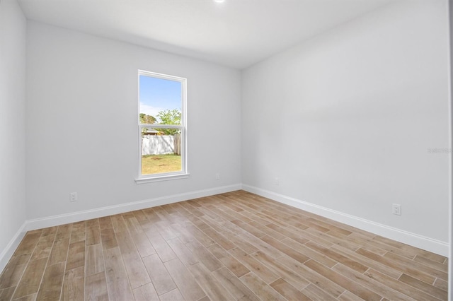 spare room featuring baseboards and light wood-style floors