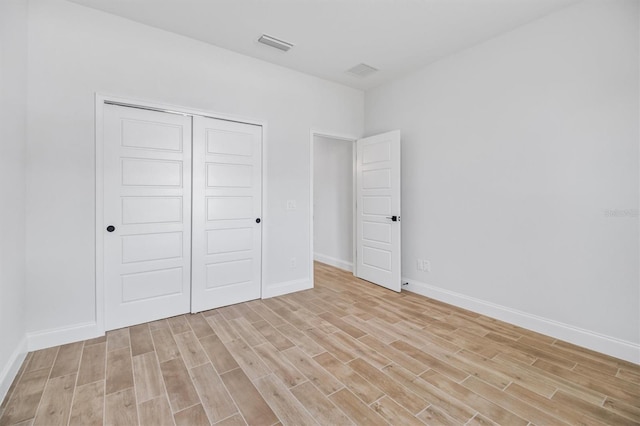 unfurnished bedroom with a closet, visible vents, light wood-style flooring, and baseboards