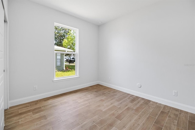 spare room featuring baseboards and light wood-style floors