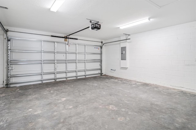 garage featuring concrete block wall, electric panel, and a garage door opener