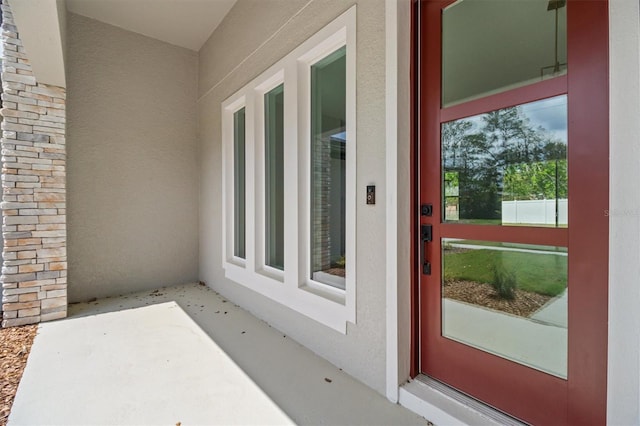 view of exterior entry featuring stucco siding and stone siding