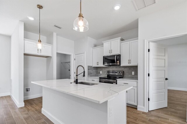 kitchen featuring visible vents, wood finish floors, tasteful backsplash, appliances with stainless steel finishes, and a sink