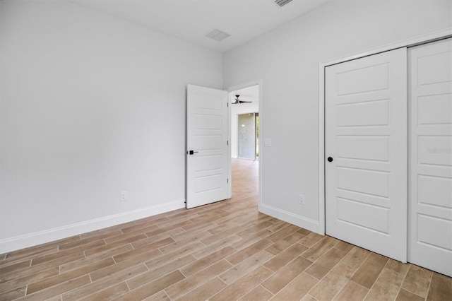 unfurnished bedroom with light wood finished floors, baseboards, visible vents, and a closet