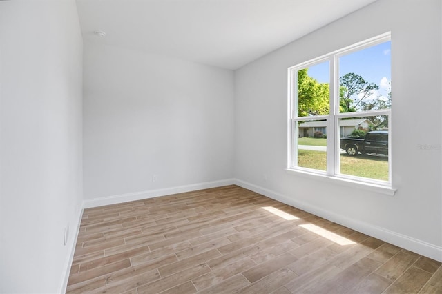 empty room featuring baseboards and light wood-type flooring