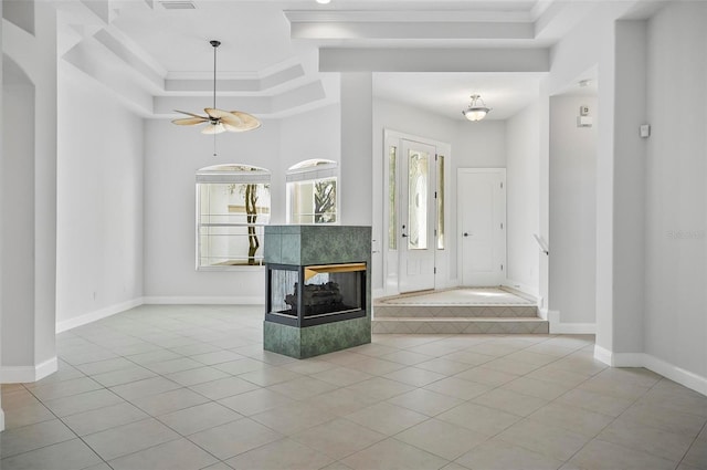 tiled foyer entrance featuring ceiling fan, crown molding, and a tiled fireplace