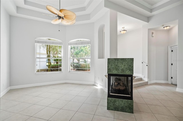 unfurnished living room with ceiling fan, light tile patterned floors, crown molding, and a tray ceiling