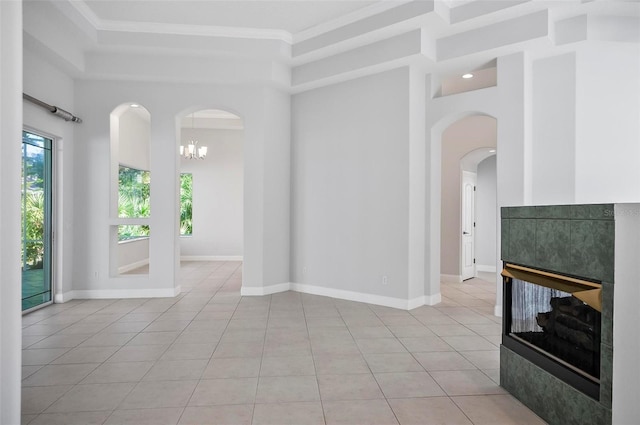 tiled empty room with a tiled fireplace, a high ceiling, and an inviting chandelier