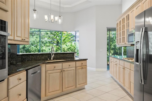 kitchen featuring an inviting chandelier, sink, dark stone countertops, decorative light fixtures, and stainless steel appliances