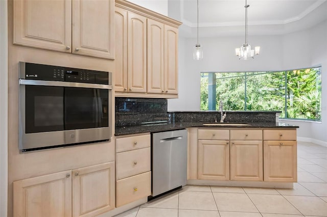 kitchen featuring light brown cabinets, sink, stainless steel appliances, and dark stone counters