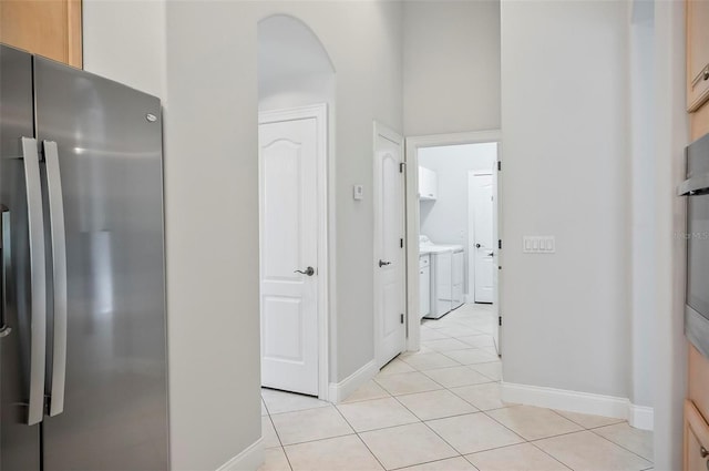 hall featuring light tile patterned floors and independent washer and dryer