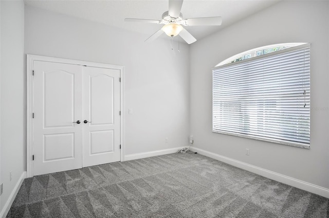 unfurnished bedroom featuring a closet, dark carpet, and ceiling fan