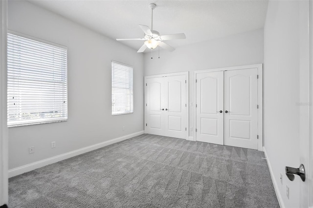 unfurnished bedroom with carpet, ceiling fan, and two closets