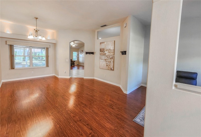 spare room with a notable chandelier and wood-type flooring